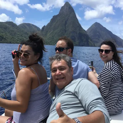 Four people on a boat trip in sunny weather with mountains in the background.