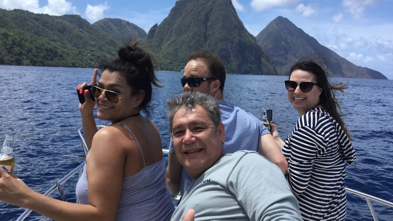 Four people on a boat trip in sunny weather with mountains in the background.