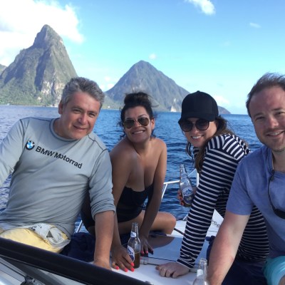 Four people on a boat with mountains and water in the background.